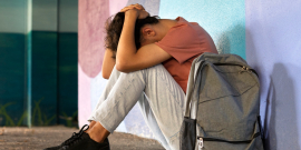Adolescente sentado com as mãos na cabeça