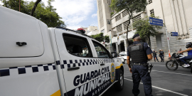 agente da guarda municipal ao lado de viatura