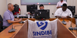 Vereadores em reunião no Plenário Camil Caram; bandeira do Sindibel está erguida na frente da mesa do presidente da comissão