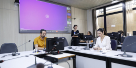 Vereadores no Plenário Helvécio Arantes, sentados com microfones na mesa à frente deles, e um telão atrás.