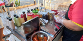 mulher prepara alimento em carro de venda de cachorro quente
