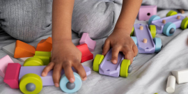 Mãos de crianças brincam com carrinhos de plástico