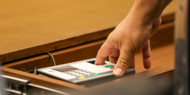 mãos de parlamentar operando terminal de votação