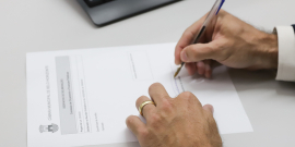 Mão de vereador enquanto assina documento durante reunião na CMBH