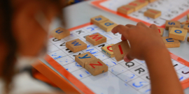 Foco em mão de criança brincando com letras em escola municipal