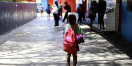 Criança com mochila de costas em ambiente escolar