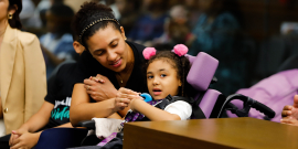 mulher ao lado de criança do sexo feminino e cadeirante