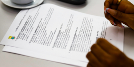 Mãos de vereadora em cima de folha com a pauta da reunião da comissão de direitos humanos