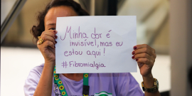 mulher segura cartaz com os dizeres minha dor é invisível mas eu estou aqui
