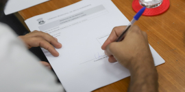 Mão de vereador assinando requerimento durante a comissão