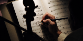 mãos de pessoa fazem anotação em partitura