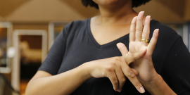 Pessoa faz sinal de Libras com as mãos
