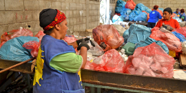 Mulher em frente a sacos de lixo reciclável