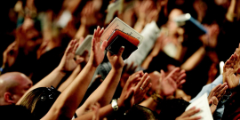 pessoas com o braço levantado em culto religioso