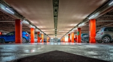 Imagem de estacionamento subterrâneo com veículos parados à esquerda e à direita