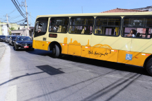 ônibus tem dificuldade de fazer conversão em via de mão dupla em razão da presença de veículos no sentido contrário. Fila de carros se forma para aguardar a manobra do ônibus