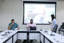 Parlamentares compõem mesa de reunião. Telão ao fundo em videoconferência com os demais membros