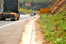 trecho de rodovia, com caminhão trafegando, sem acostamento ou áreas de escape. Placa indica redução de velocidade