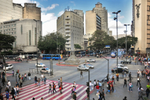 Vista aérea da Praça Sete, com pessoas e carros transitando, durante o dia. 