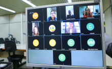 Três homens e duas mulheres dividem tela de computador em audiência pública remota. 