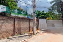 Muro de construção com Cartaz de duas torres de prédios com mais de dez andares ao fundo e dois cartazes indicando Residenciais Cartagena, Módulos I e II, à frente, durante o dia. 