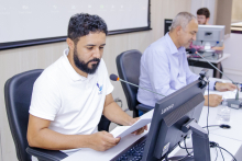 Dois vereadores participam de reunião, sentados à mesa.