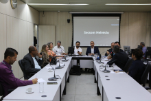 Oito homens e três mulheres sentados à mesa, conversando. 