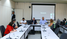 Duas mulheres e quatro homens reunidos à mesa. 