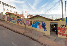 Fachada do Centro de Saúde Campo Alegre, com borboletas, coração e outras imagens coloridas pintadas em muro amarelo, durante o dia.