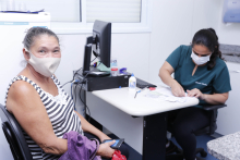Cidadão, sentada, é atendida por profissional de saúde em consultório