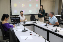 Três vereadores participam de reunião, sentados à mesa.