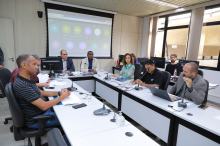 Seis homens e uma mulher reunidos, sentados à mesa