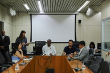 Três vereadores participam de reunião, sentados à mesa.