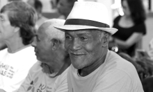 Dois idosos sentados, um deles está com chapéu de palha.
