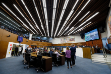 Vereadores se reúnem presencialmente na primeira reunião do Plenário da 20ª Legislatura. A foto mostra vereadores sentados e em pé, em visão lateral, bem como a mesa diretora e o telão.