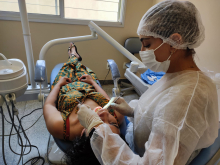 profissional de saúde realiza atendimento odontológico em mulher deitada em maca