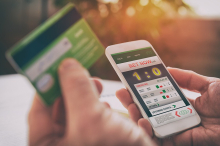 close nas mãos de pessoa segurando um celular com jogo de apostos na tela