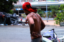 homem sem camisa visto de costas ao lado de um carrinho de supermercado