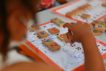 Foco em mão de criança brincando com letras em escola municipal