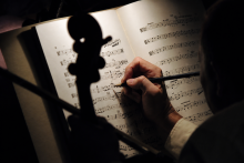 mãos de pessoa fazem anotação em partitura